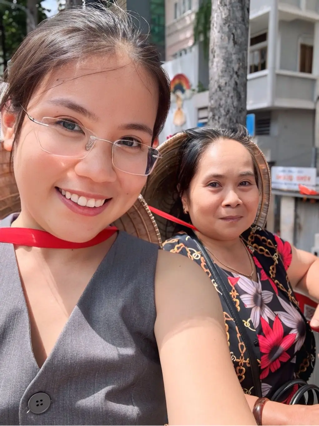 Loo đeo kính, cười cùng một người thân đội nón lá