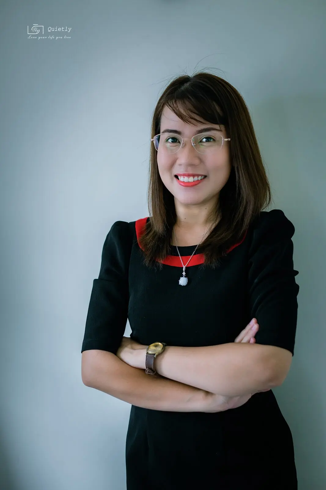 Chân dung Loo mặc váy đen, khoanh tay, đeo kính