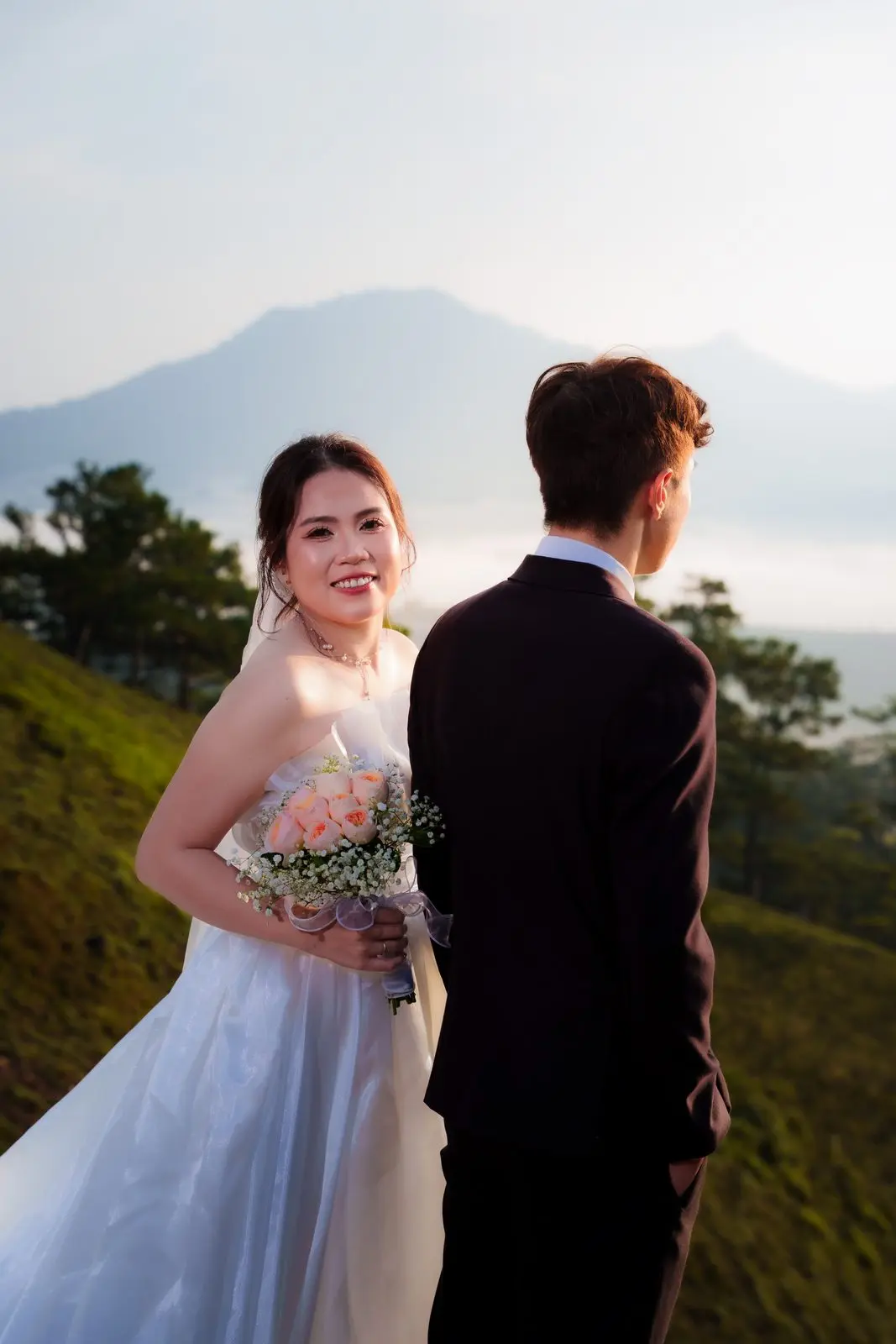 Loo ôm bó hoa, cười tươi bên Boo, núi mờ phía sau