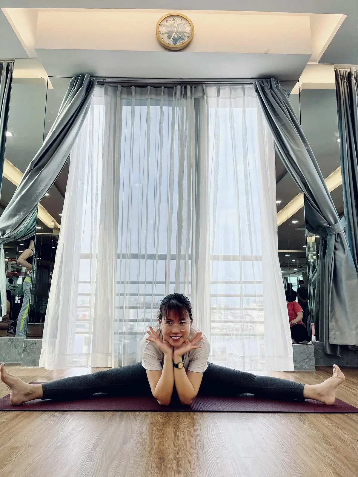 Loo xoạc chân trên thảm yoga, hai tay chống cằm cười