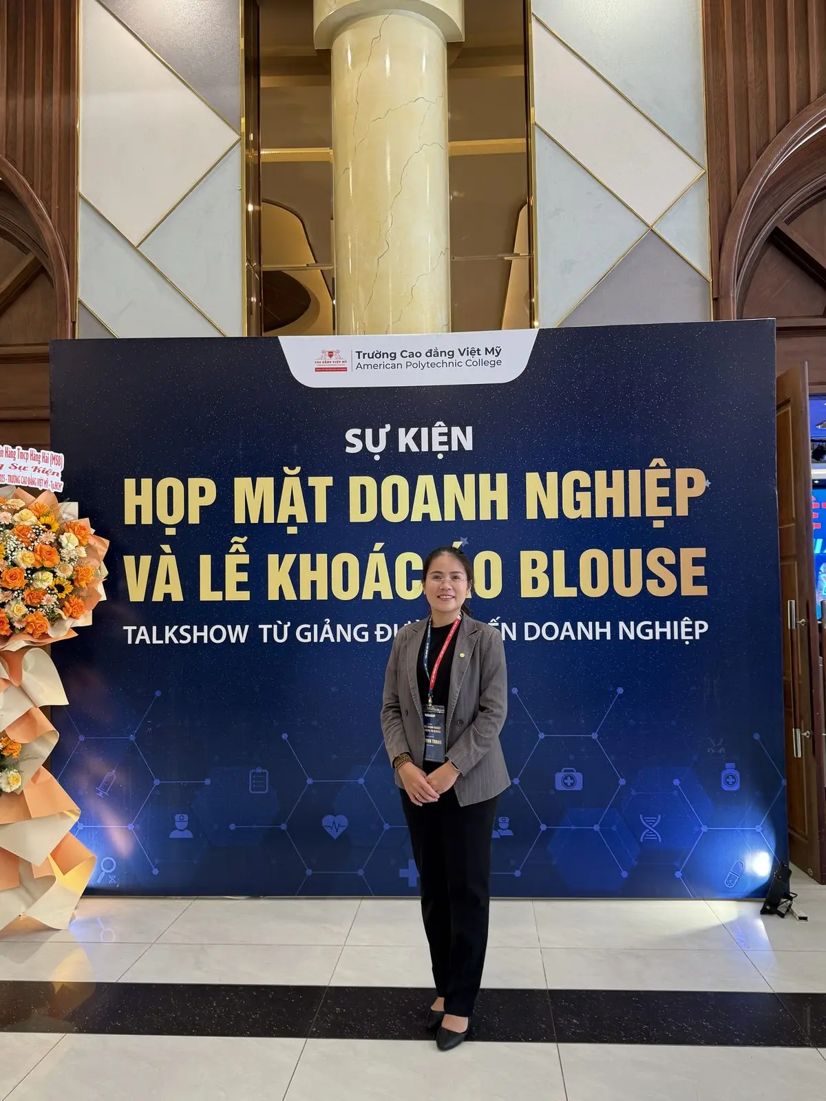 Loo đứng trước phông sự kiện họp mặt doanh nghiệp và lễ khoác áo blouse