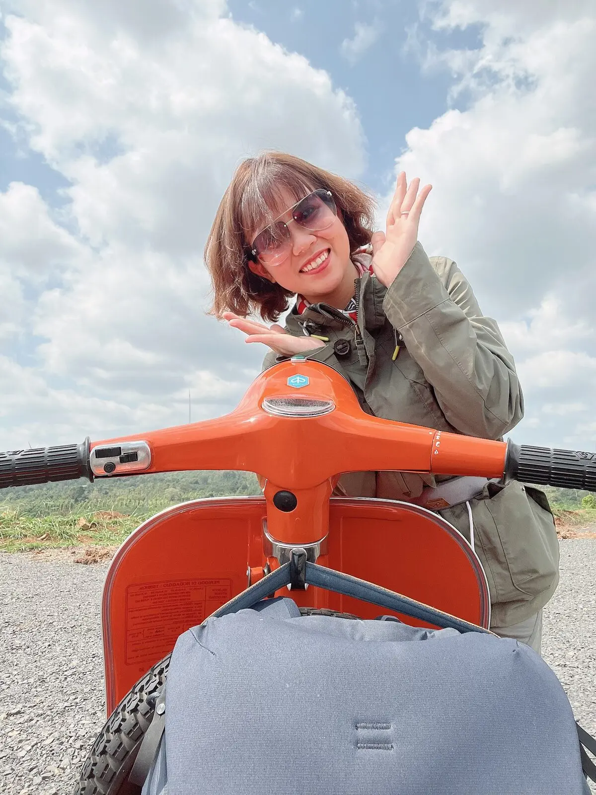 Loo đeo kính râm sau tay lái chiếc Vespa cam giữa đồng gió Gia Lai