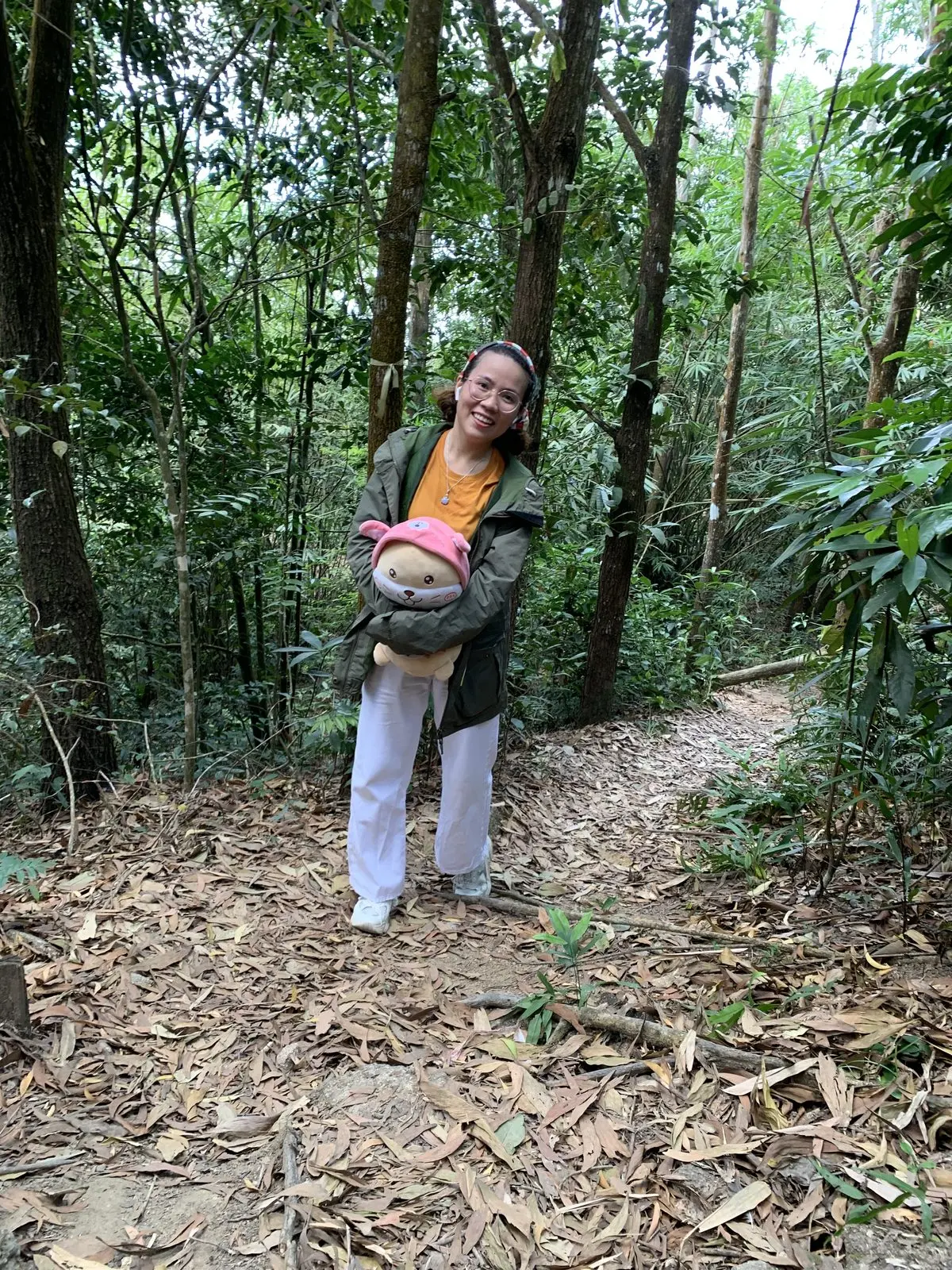 Loo ôm gấu bông đứng giữa rừng cây