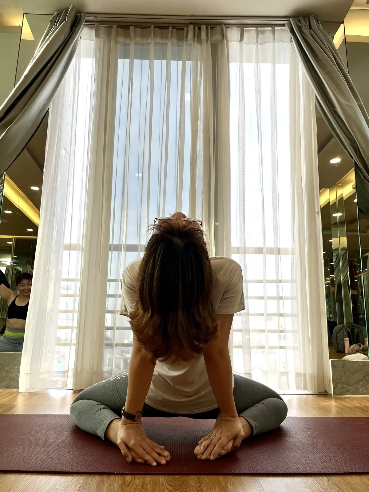 Loo ngồi tập yoga trước khung cửa kính rèm trắng