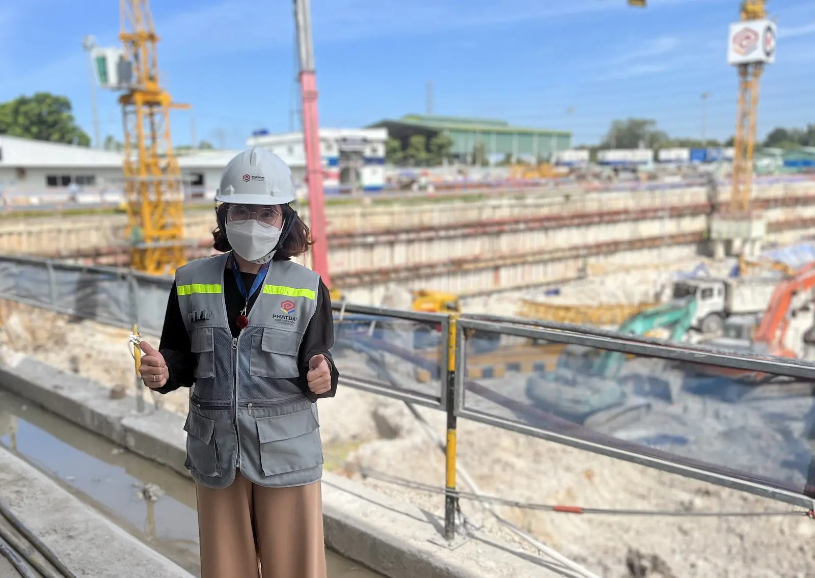 Loo đội mũ bảo hộ, mặc áo phản quang đứng cạnh hố móng công trình