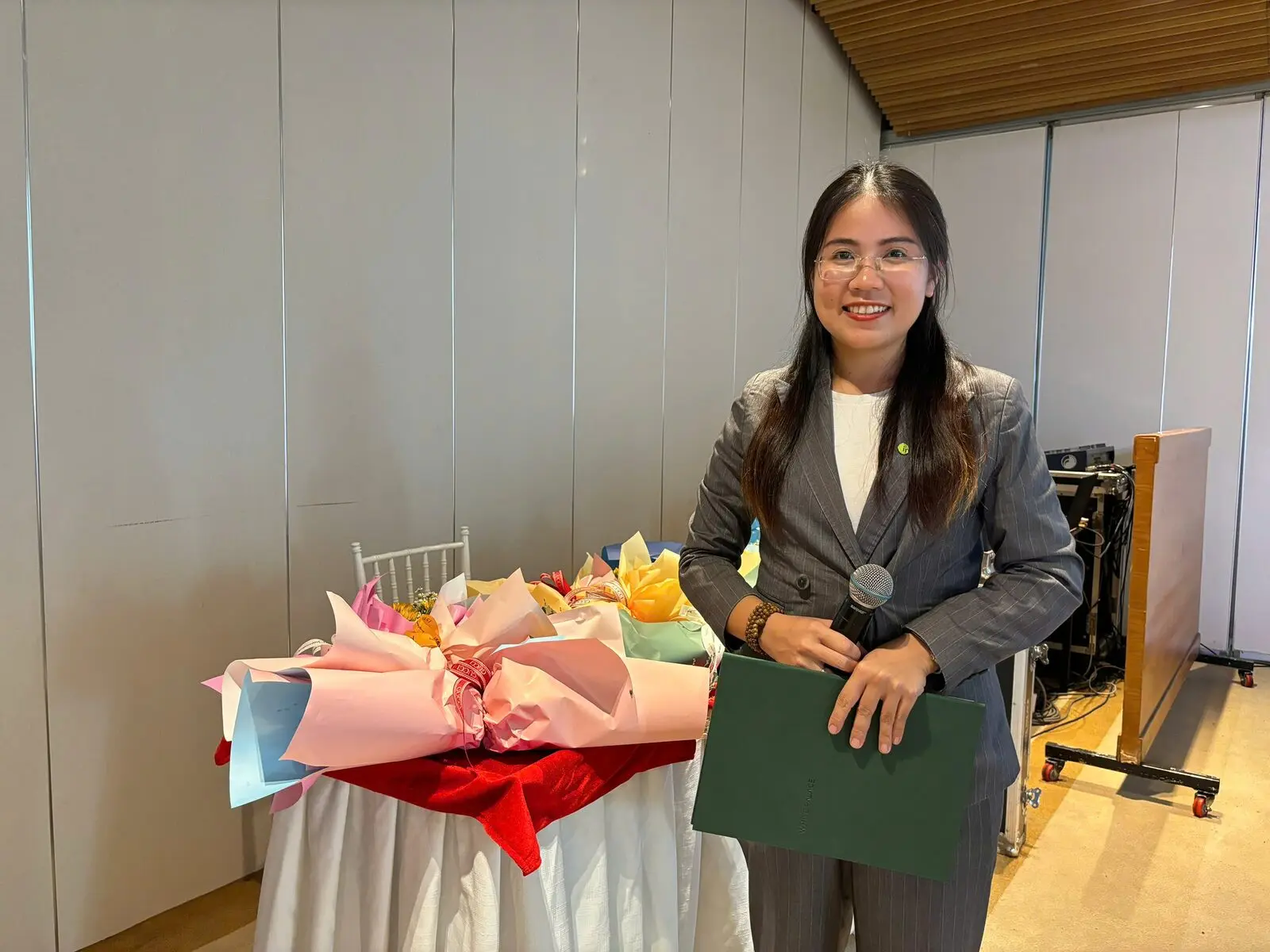 Loo cầm mic và tập kịch bản, cười bên bàn hoa trong lễ tốt nghiệp