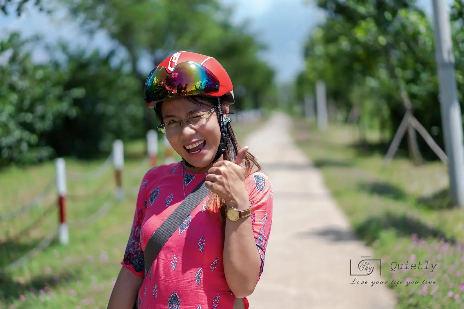 Loo đội mũ bảo hiểm, đeo kính, cười trên con đường nhỏ