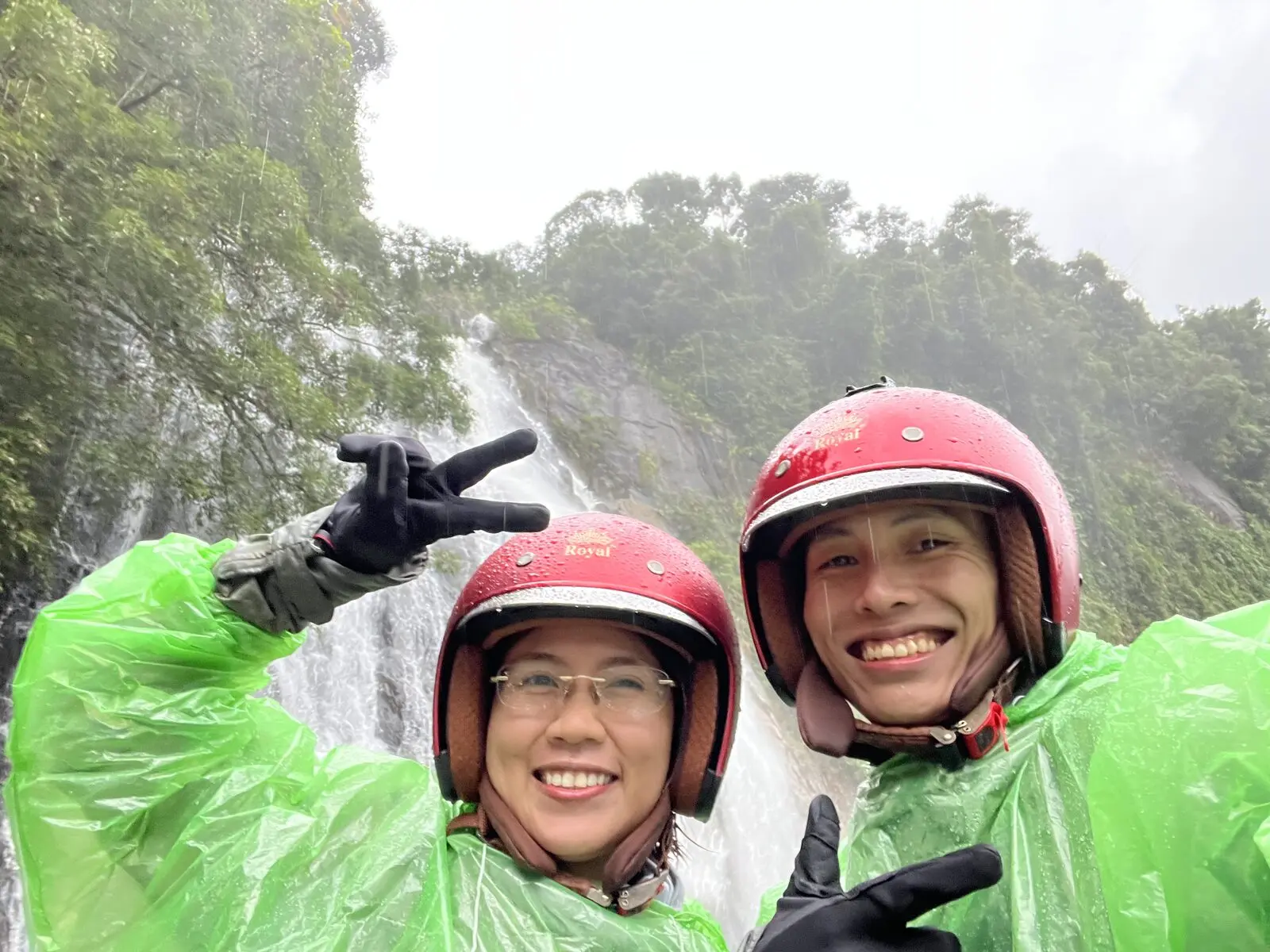 Loo và Boo mặc áo mưa xanh bên thác nước ở Nam Giang