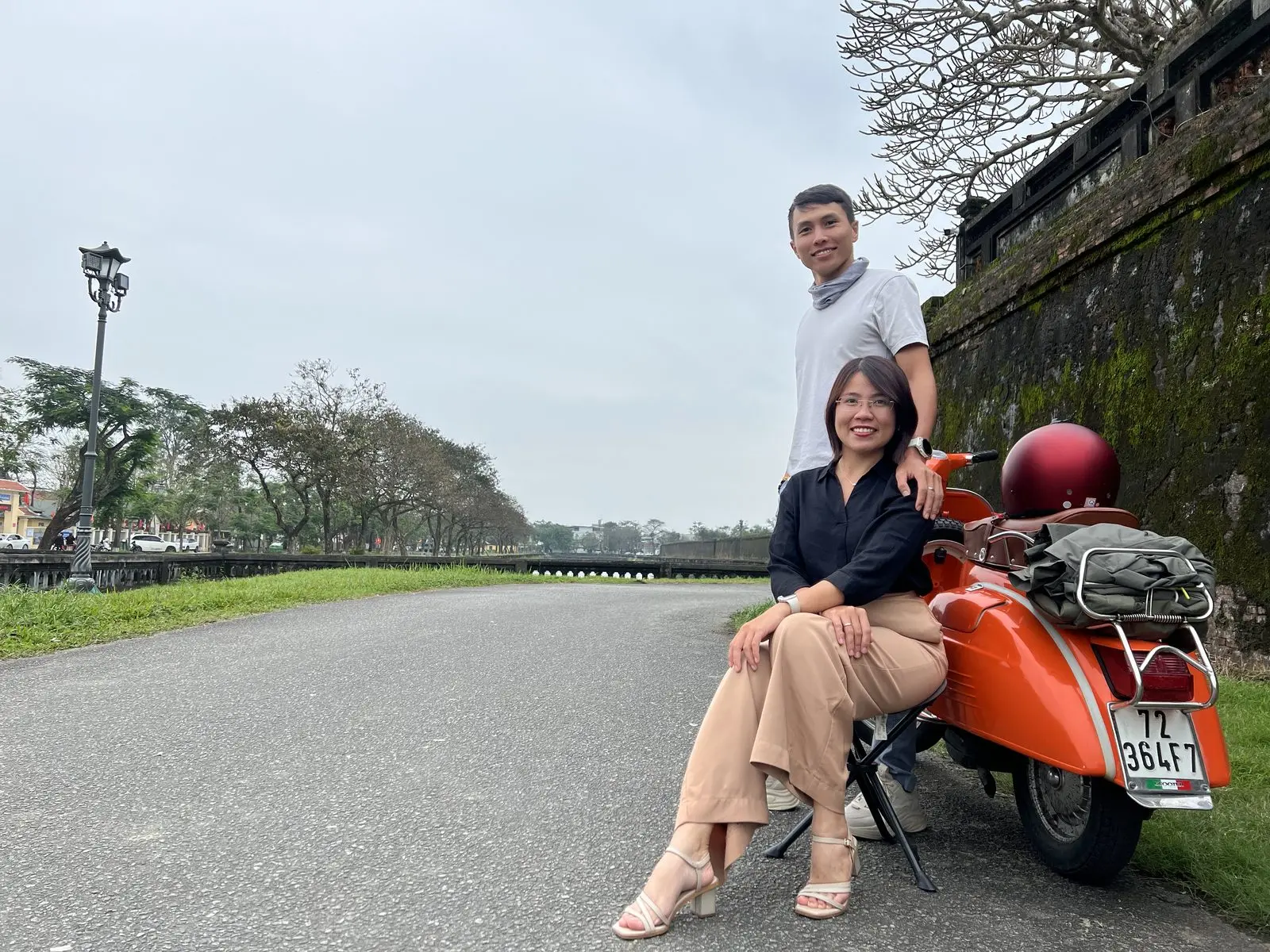 Loo ngồi trên chiếc Vespa cam, Boo đứng cạnh bên tường thành
